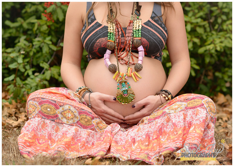 pregnant mother sitting with hands on belly and african necklaces
