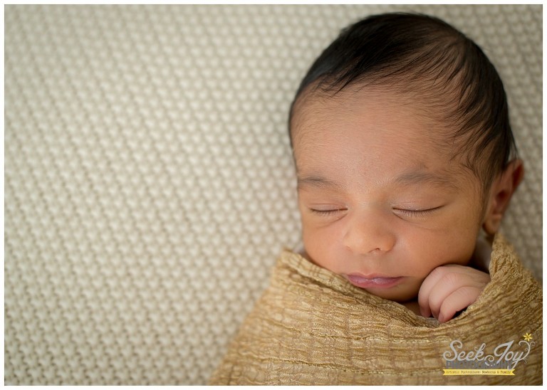 newborn boy wrapped in golden scarf