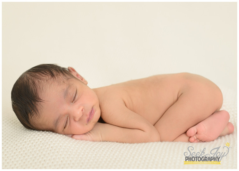 Newborn baby boy on cream blanket posed
