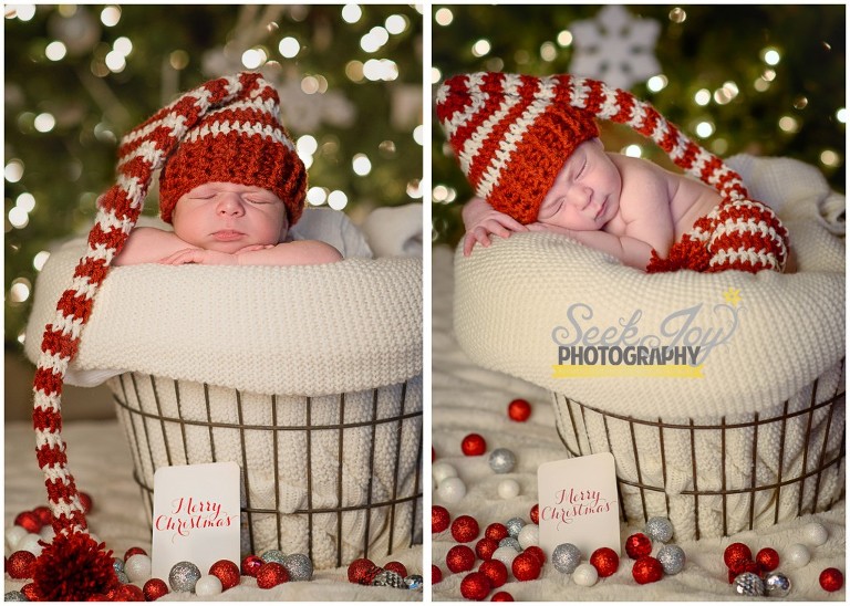 newborn sleeping in front of Christmas tree wearing striped elf hat