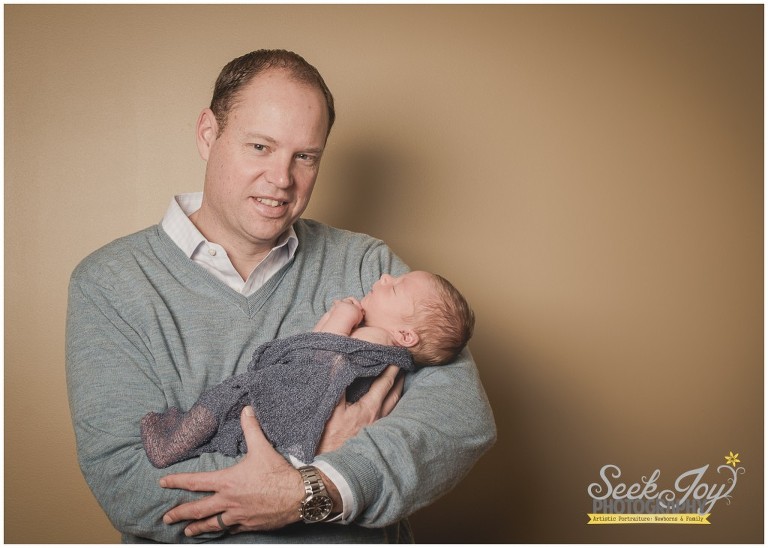 indoor portrait of father holding his son, newborn photography in greenville