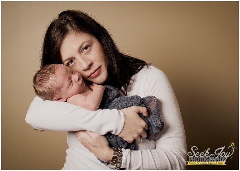 indoor portrait of mother holding newborn son closer to her face
