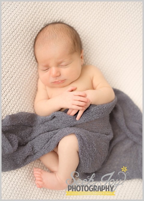 newborn boy sleeping on back with blue wrap